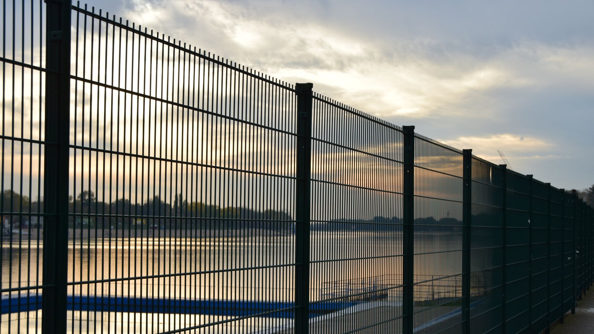 High security metal fence with sunset sky and distant landscape
