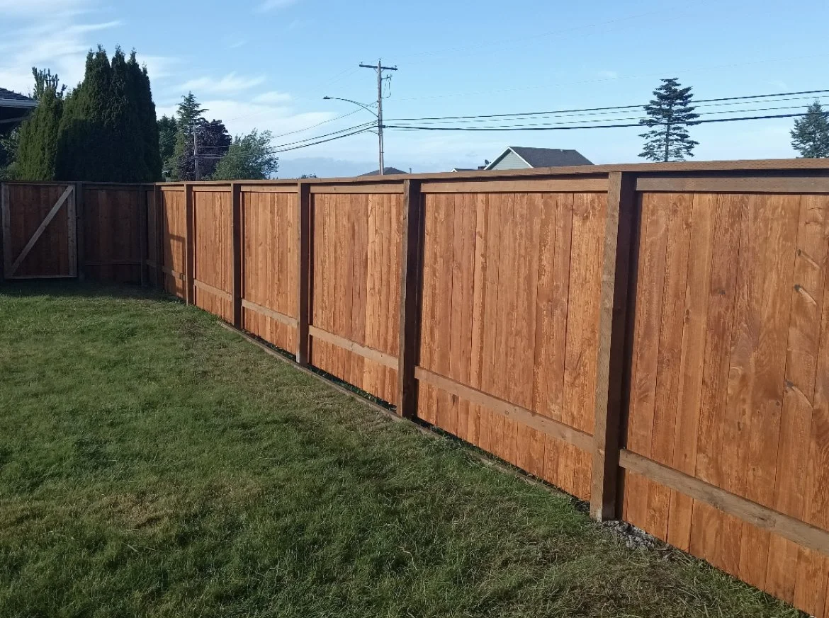 Wooden privacy fence with brown panels bordering a green lawn