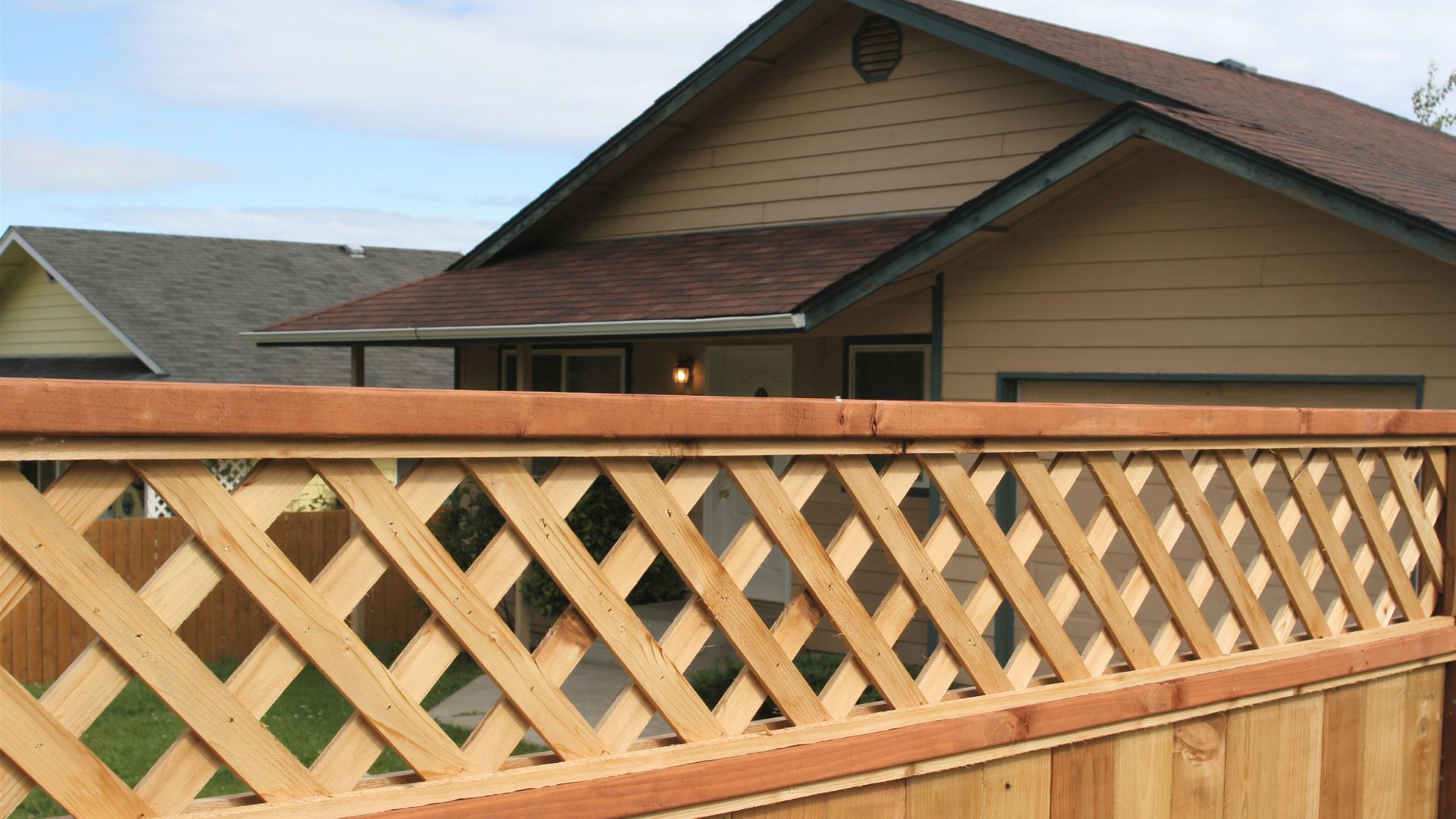 Wooden lattice fence with crisscross pattern in front of suburban house